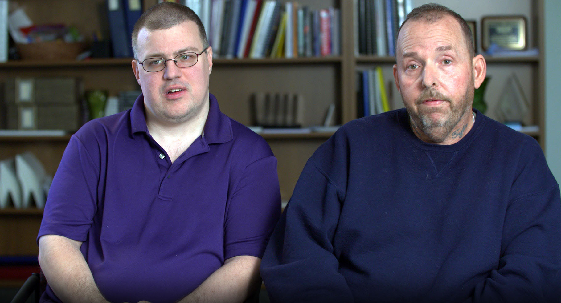 This photo is at the top of the opening page for the article We’re Talking About Lives Here: The Personal Impact of the Direct Support Workforce Crisis.  The photo shows Shawn Fultz seated on the left next to Jim Friss on the right, with a set of bookshelves in the background. They’re facing the camera and have serious looks on their faces. 