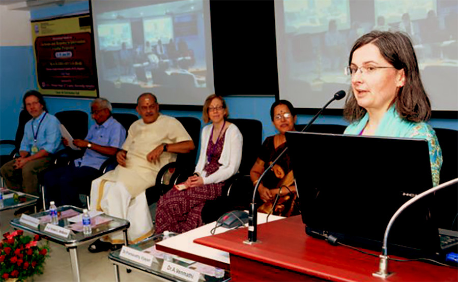 Photo of Renáta Tichá presenting at the International Summit with other organizers and presenters in the background.